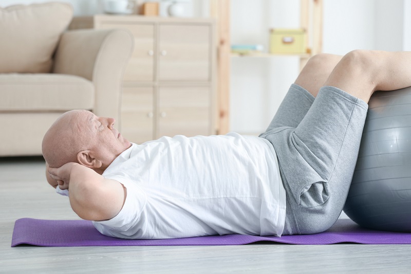 Um senhor fazendo abdominal usando uma bola de exercício. Imagem para ilustrar a matéria sobre peso ideal.