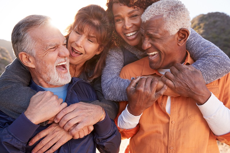Quatro amigos se divertem juntos, sendo duas mulheres e dois homens. A imagem ilustra o artigo sobre proteção previdenciária.