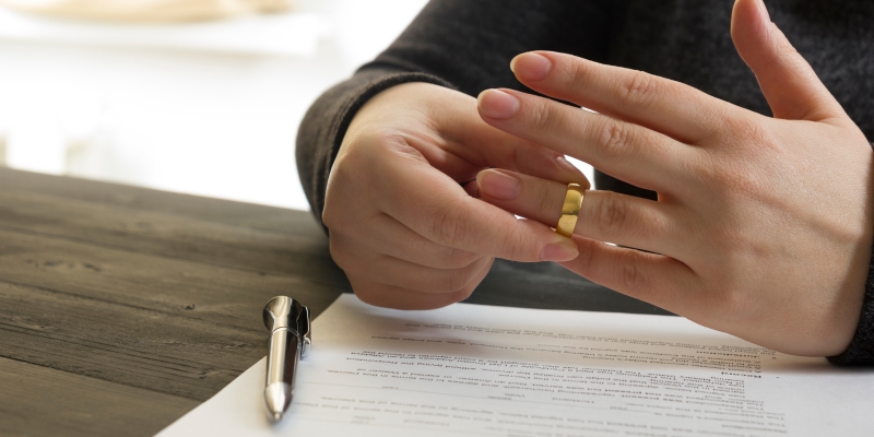 Uma mulher retirando a alinaça dos dedos após assinar os papéis do divórcio online.