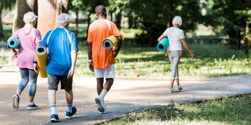 Um grupo de pessoas idosas indo fazer exercício físcio, em um parque. Ato todo são duas mulheres e dois homens e todos carregam tapetes de exercícios. Imagem para ilustrar a matéria sobre declínio cognitivo.