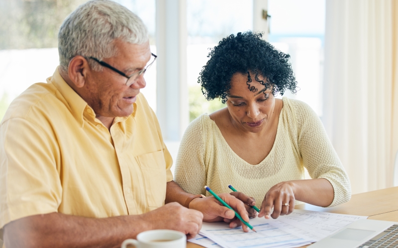 Um casal de aposentados organizando as finanças, após ver como economizar dinheiro em 11 passos.