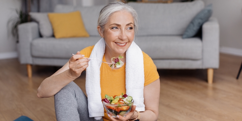 Uma mulher, com roupa de exercícios, comendo salada. Imagem para ilustrar a matéria sobre dieta do tipo sanguíneo.