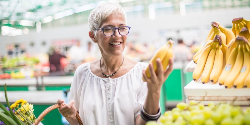 Uma mulher de meia idade fazendo feira no mercado. Imagem para ilustrar a matéria sobre o que comer para viver mais.