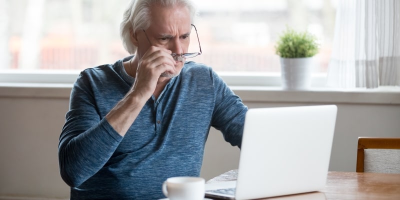 Um homem idoso olhando para o computador, como se algo estivesse errado. Imagem para ilustrar a matéria sobre segurança na internet.