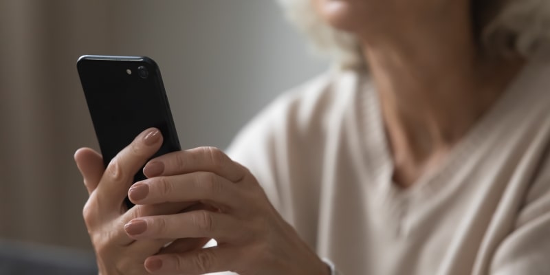 Uma mulher idosa olhando para o celular. Imagem para registrar a matéria sobre digitalização de planos de saúde.