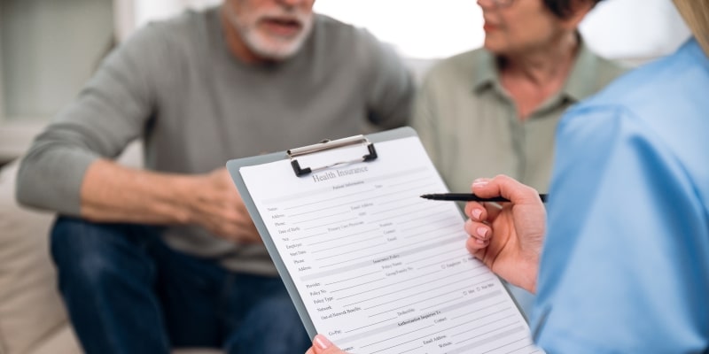Um casal de idosos assinando um contrato de plano de saúde. Imagem para ilustrar a matéria sobre os direitos dos idosos nos planos de saúde.