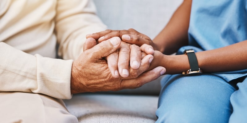 Profissional da saúde segurando as mãos de uma pessoa idosa em tratamento de depressão. Imagem para ilustrar a matéria sobre como ajudar alguém com depressão.