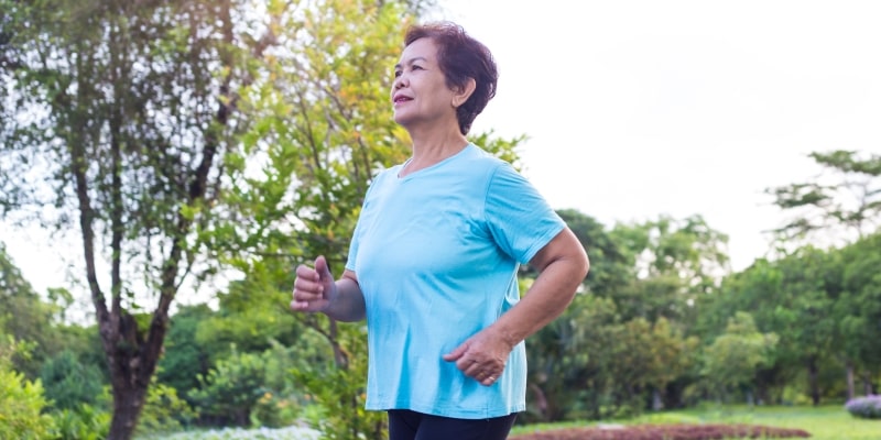 Uma senhora correndo em um parque. Imagem para ilustrar a matéria sobre importância da natureza para a saúde dos idosos.