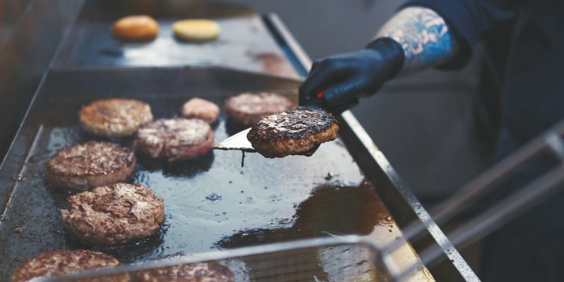 Cozinheiro profissional fritando carne bovina na panela na cozinha do restaurante. Imagem para ilustrar a matéria sobre alimentos que não devem ser consumidos.
