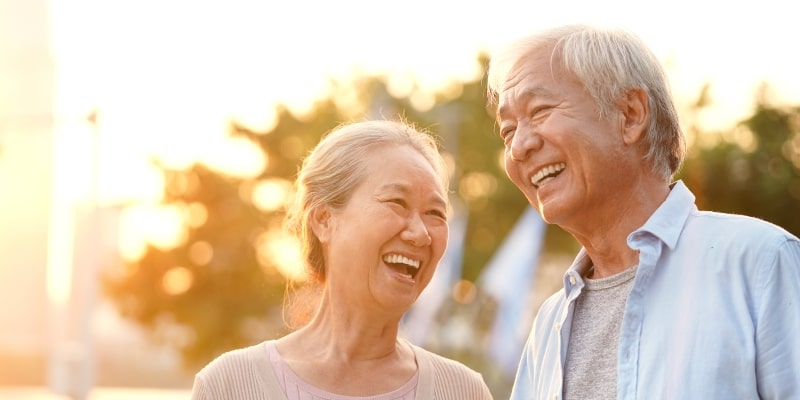 casal asiático sênior desfrutando de bons momentos ao ar livre no parque ao entardecer, feliz e sorridente. Imagem para ilustrar a matéria sobre longevidade aumentou.