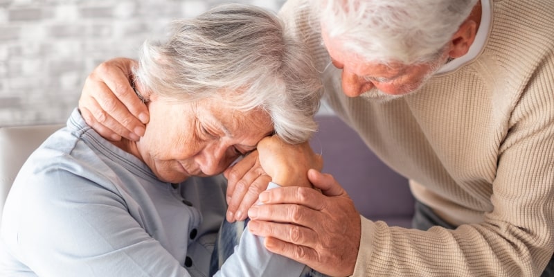 Homem idoso confortando sua esposa deprimida. Imagem para ilustrar a matéria sobre a importância da saúde mental de pessoas idosas.