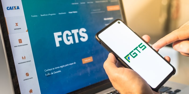 Uma pessoa acessando o FGTS pelo celular e pelo computador. Imagem para ilustrar a matéria sobre FGTS Digital.