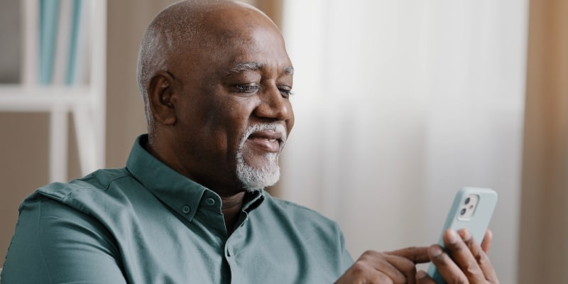 Um homem idoso negro mexendo no celular. Imagem para ilustrar a matéria sobre a ferramenta Não Perturbe.