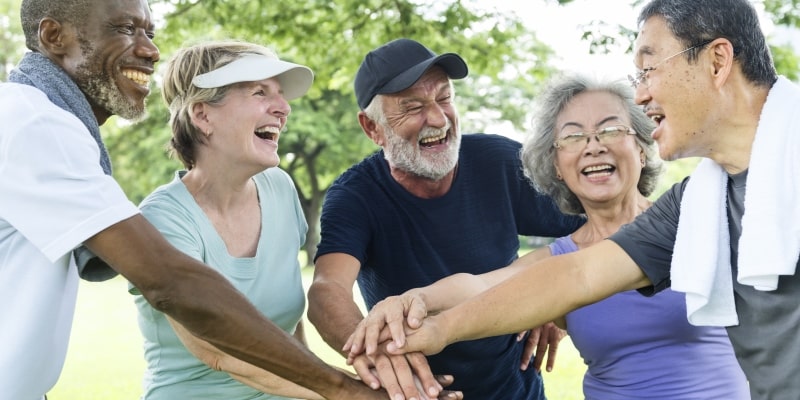Um grupo de idosos felizes, participando de uma atividade física ao ar livre. Imagem para ilustrar a matéria sobre a Virada da Maturidade.