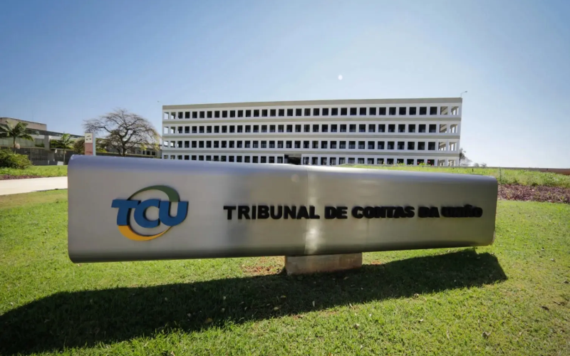 Placa com logomarca do TCU escrito Tribunal de Contas da União, órgão que identificou descontos indevidos para aposentados do INSS, no gramado.