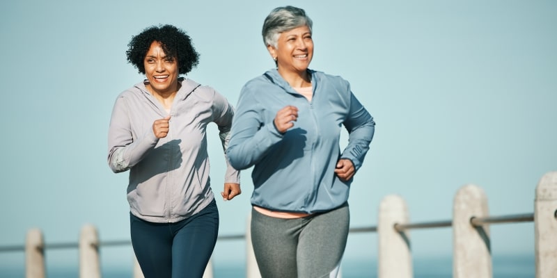 Duas mulheres de meia idade correndo em área aberta, praticando healthspan.