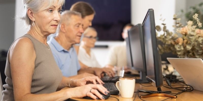 Senhora idosa de cabelos grisalhos usando o computador, demonstrando a curiosidade dos idosos modernos em relação à tecnologia. Imagem para ilustrar a matéria sobre transição de carreira após os 50.