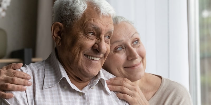 Um casal de idosos sorrindo e olhando para o horizonte. Imagem para ilustrar a matéria sobre os sonhos das pessoas acima de 65 anos.