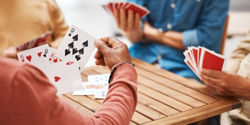 Um grupo de idosos jogando cartas, um dos tipos de atividades sociais fortalecem o cérebro.