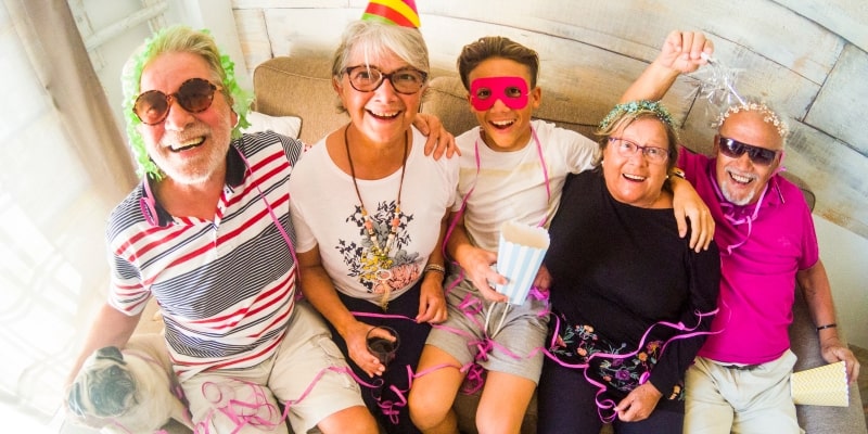 Carnaval para idosos que gostam de curtir em casa. Um grupo de idosos curtindo o carnaval sentados no sofá.