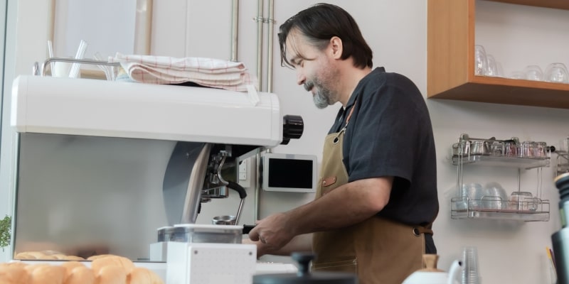 Um homem, em torno de 50 anos, praticamento o empreendedorismo sênior ao ter a sua própria cafeteria.
