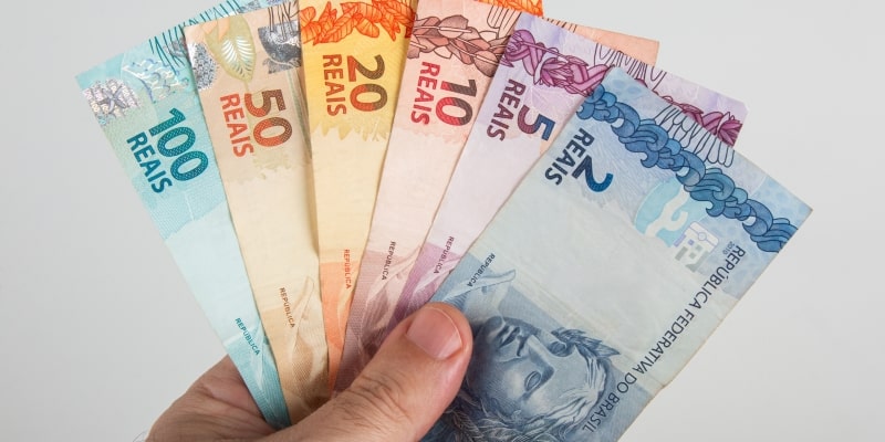 Uma mão segurando notas de dinheiro. Imagem para ilustrar a matéria sobre os pedidos de reembolso ao INSS.