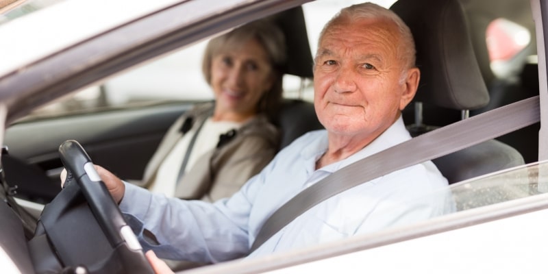 Um casal de idosos dentro de um carro. O homem dirige enquanto a mulher está no lugar do carona. Imagem para ilustrar a matéria sobe a isenção para comprar carro zero.
