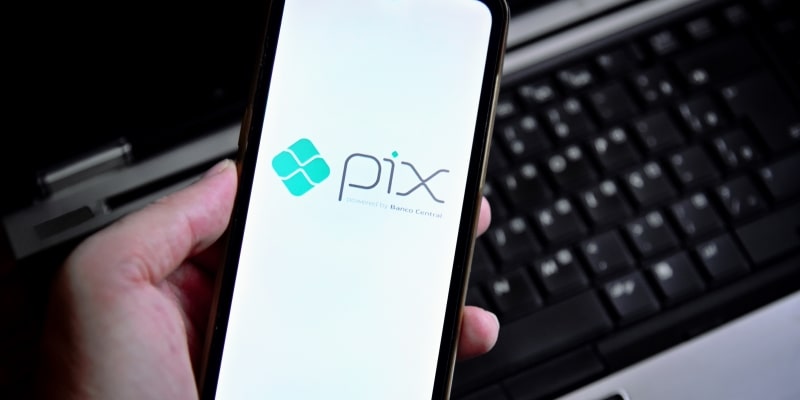 Uma pessoa segurando um celular com o ícone do pix. Imagem para ilustrar a matéria sobre o Pix automático.