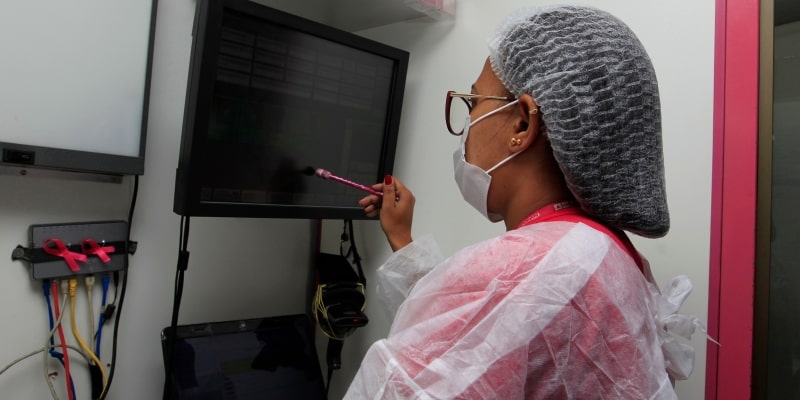 Médico ou radiologista examinando exames de mamografia para detectar sinais de câncer de mama. Imagem para ilustrar a matéria sobre idade para mamografia.