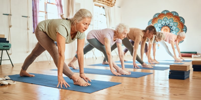 Um grupo de mulheres entre 50 e 70 anos praticando yoga. Imagem para ilustrar a matéria sobre yoga para a longevidade feminina.