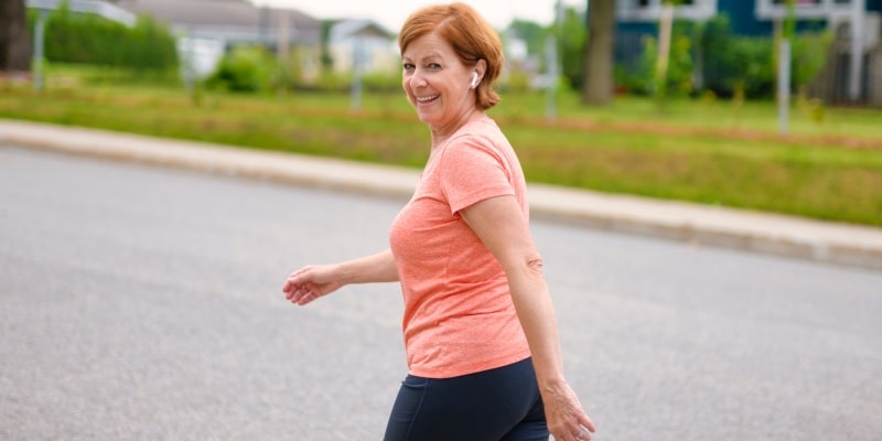 Uma mulher madura caminhando na rua. Imagem para ilustrar a matéria sobre os benefícios da caminhada.