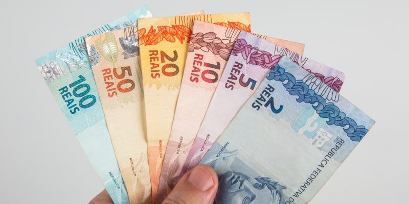 Uma mão segurando notas de dinheiro. Imagem para ilustrar a matéria sobre isenção do imposto de renda para MEI.