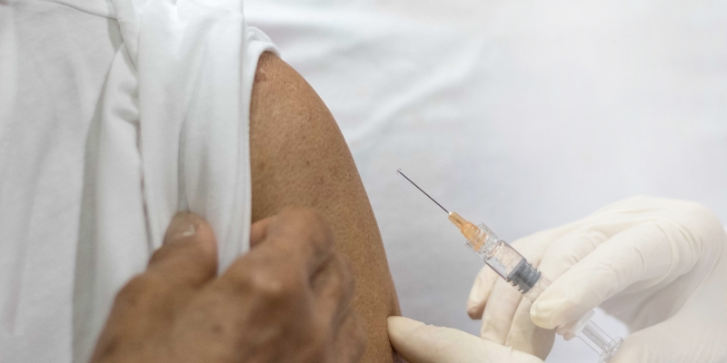 Braço de uma pessoa idosa com a manga levantada para receber a vacina contra herpes-zóster.