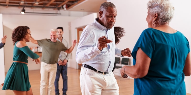 Uma aula de dança com pessoas idosas, fazendo atividades criativas para melhorar o envelhecimento do cérebro.