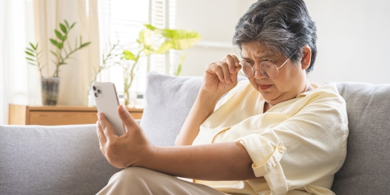 Uma mulher idosa com dificuldade para mexer no celular, ilustrando a matéria sobre exclusão digital de pessoas idosas.