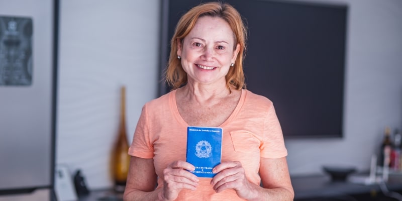 Mulher idosa trabalhando com a carteira de trabalho brasileira na mão. Imagem para ilustrar a matéria sobre o crescimento de idosos no mercado de trabalho.