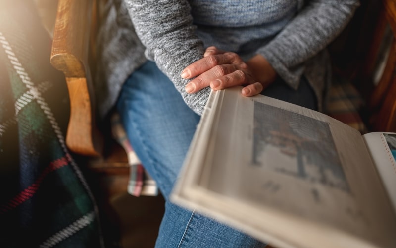 Uma mulher olhando um álbum antigo de fotos para honrar sua família.