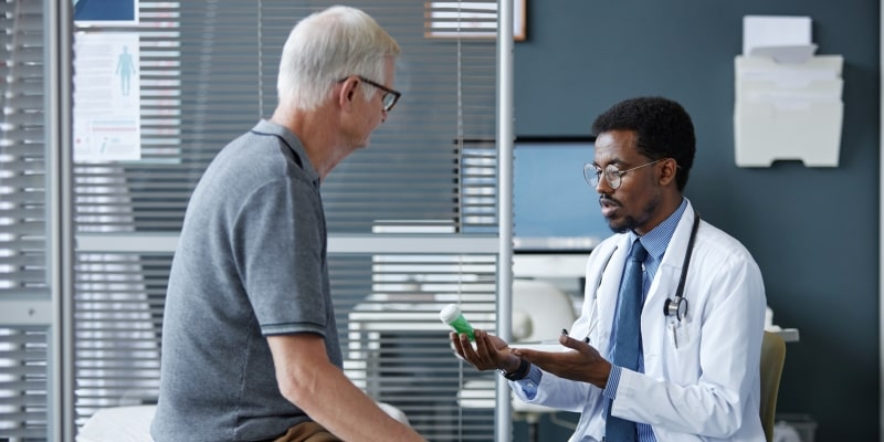 Um homem idoso em consulta médica enquanto o médico o entrega remédios para a sua saúde masculina.