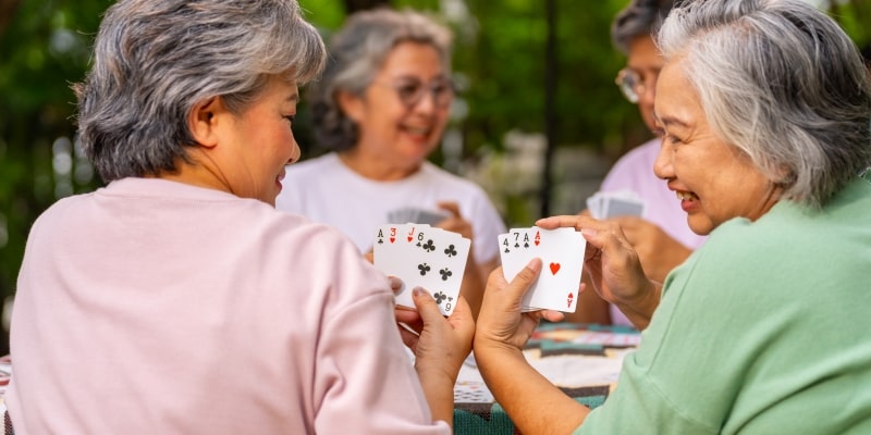 Um grupo de mulheres idosas em uma atividade social, jogando cartas e sorrindo. Imagem para ilustrar a matéria sobre o conceito de envelhecimento ativo.