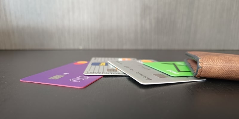 Uma carteira sobre a mesa com alguns cartões de crédito ao lado, ilustrando a matéria sobre dívida no cartão de crédito.