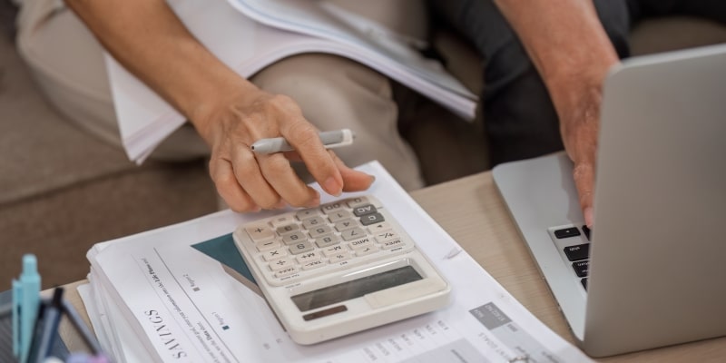 Casal de idosos gerenciando as finanças familiares com calculadora e notebook em casa para evitar erros financeiros na aposentadoria.