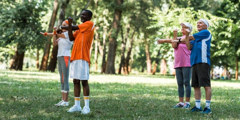 Um grupo de idosos fazendo atividade física guiada em uma área verde, ilustrando a matéria sobre oportunidades de investimento no envelhecimento.