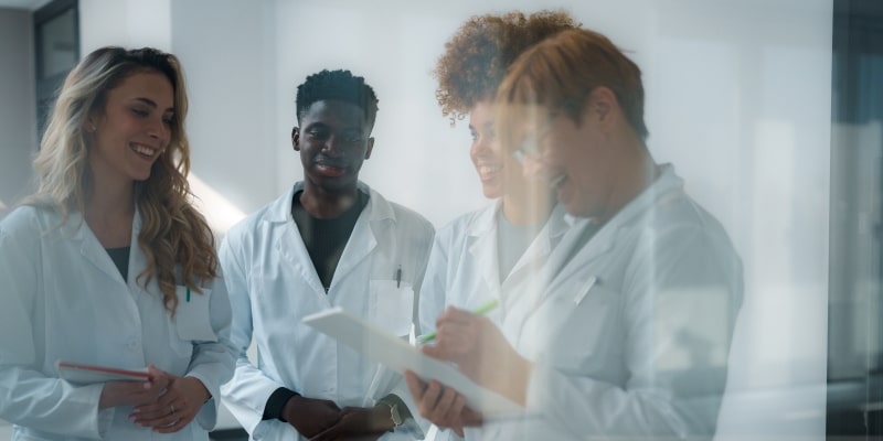Jovens estudantes de jaleco reunidos enquanto estudam para profissões da longevidade.