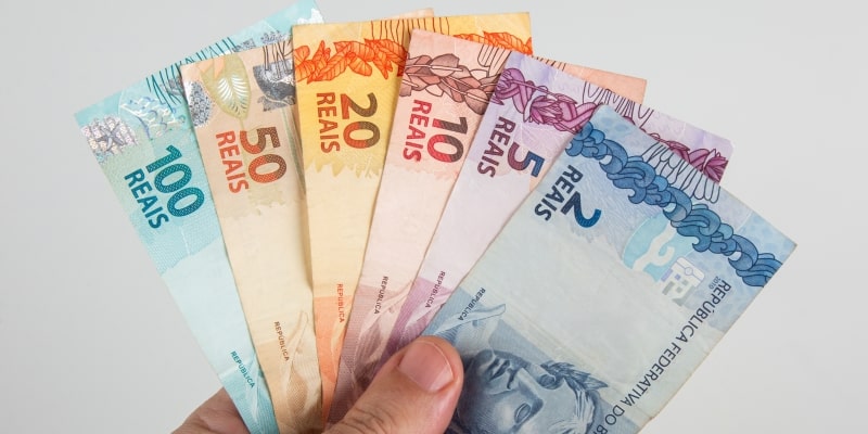 Uma mão segurando notas de dinheiro, ilustrando a matéria sobre como atrair dinheiro em 2026.