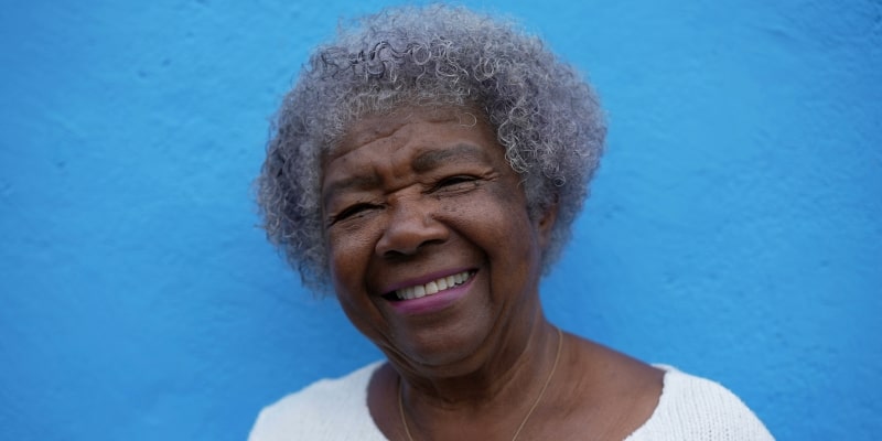 Uma mulher idosa negra sorrindo. Imagem para ilustrar a matéria sobre a genética da longevidade.