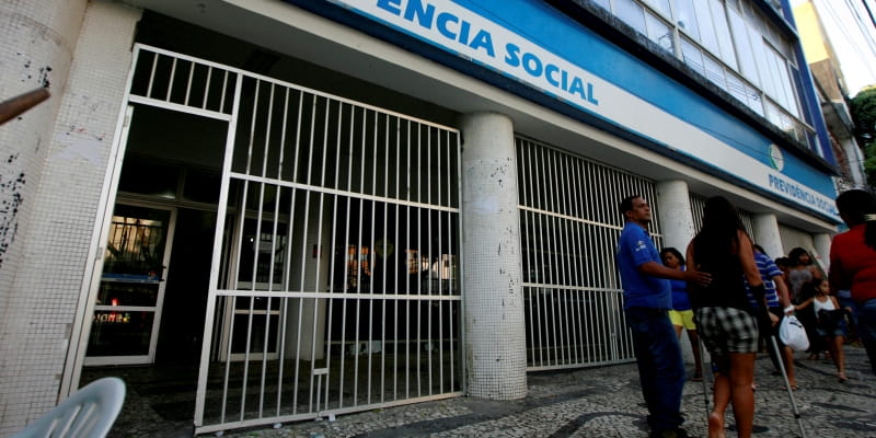 Uma mulher de muleta saindo de uma agência do INSS. Imagem para ilustrar a matéria sobre como solicitar auxílio-doença.