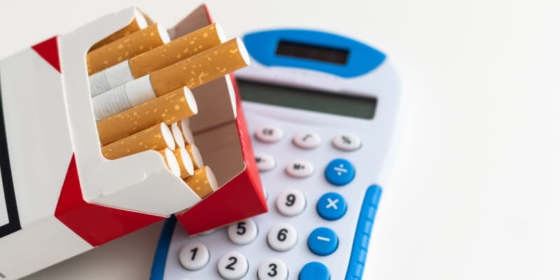 Um maço de cigarro sobre uma calculadora, ilustrando a matéria sobre largar o cigarro.