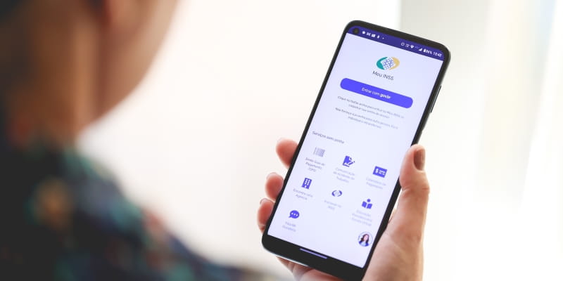 Uma mulher acessando o Meu INSS pelo celular para ver informações sobre o auxílio-doença sem perícia.
