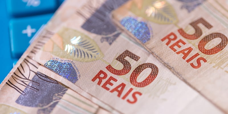 Notas de 50 reais sobre uma calculadora, ilustrando a matéria sobre o Feirão Limpa Nome 2026