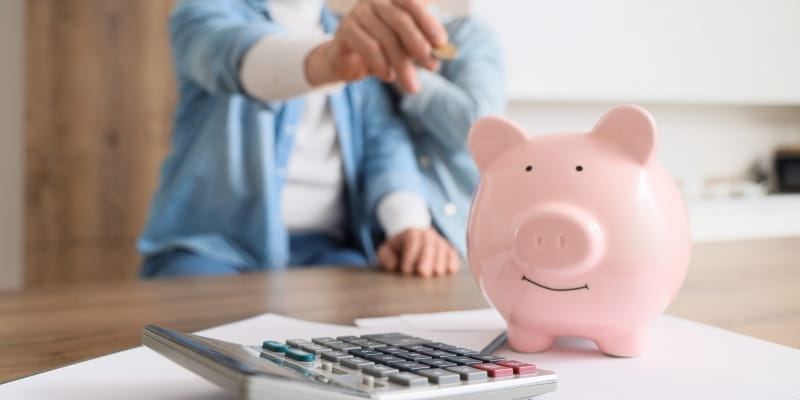 Casal maduro colocando moedas no cofrinho. Imagem para ilustrar a matéria sobre hábitos financeiros para a saúde mental.